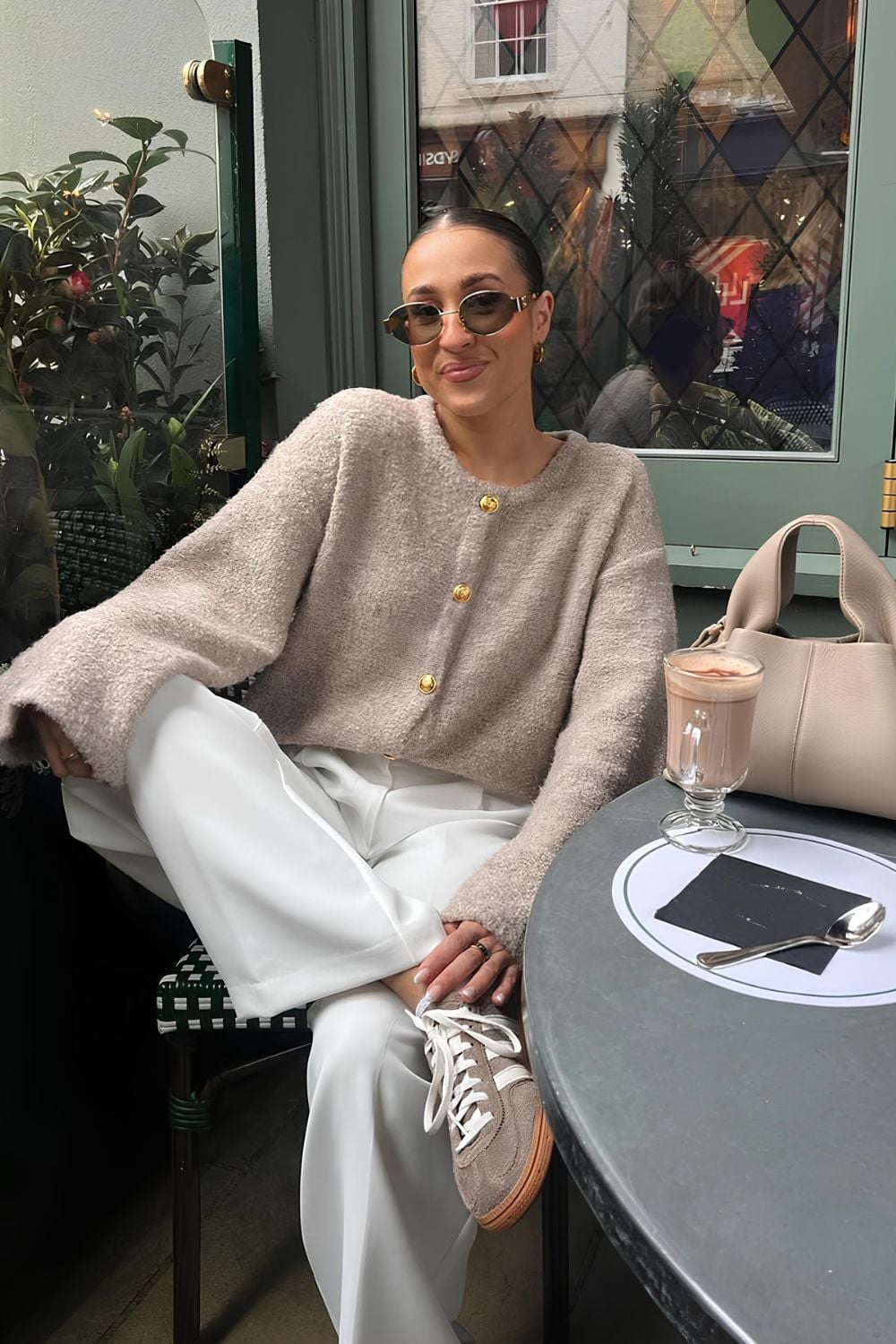 Beige button up sweater and white pants paired with sneakers