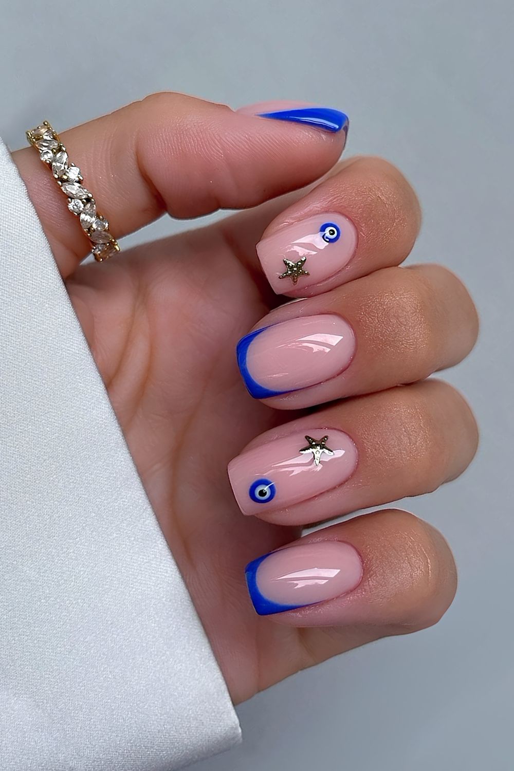 Cobalt blue French tips with starfish and evil eye accents