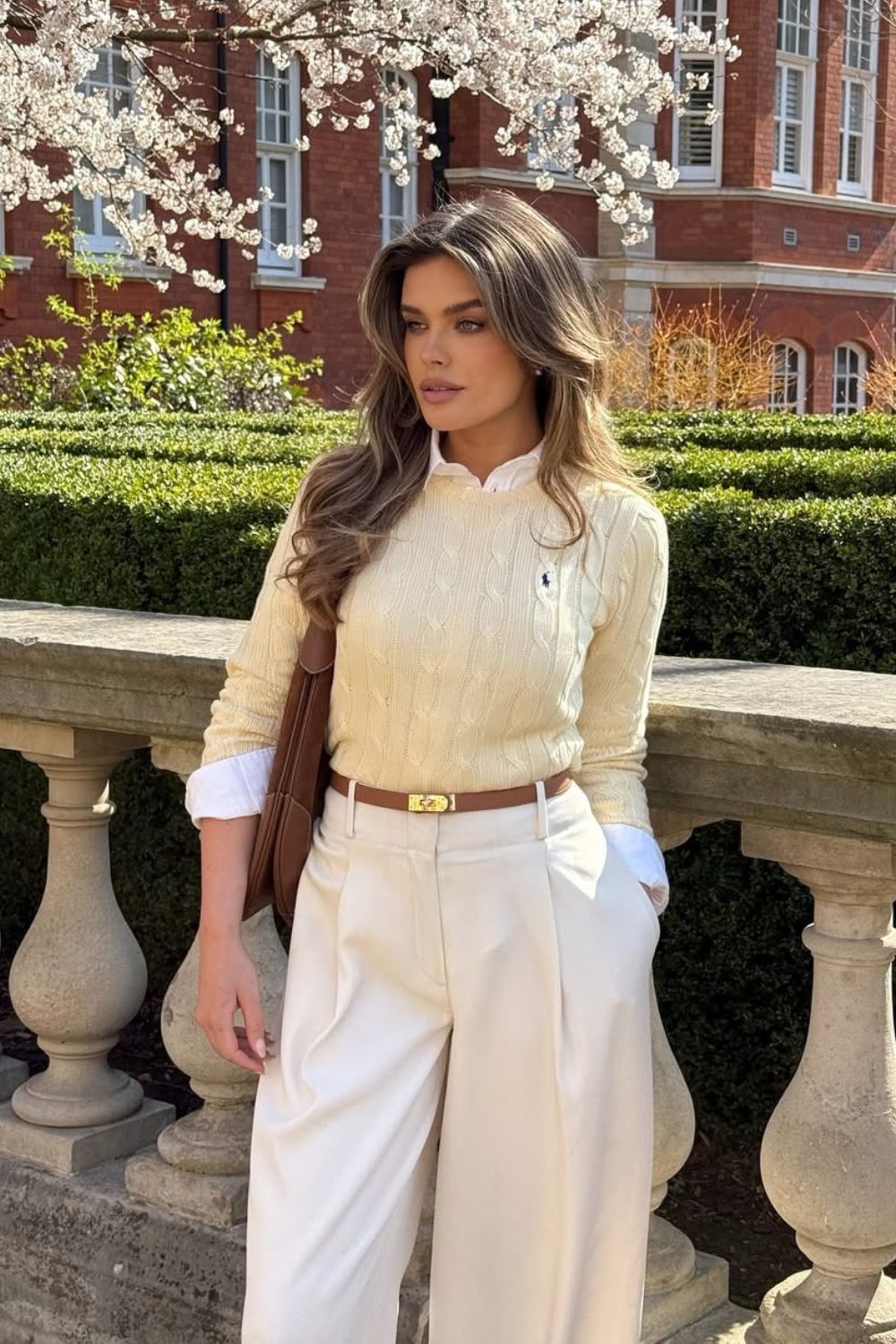 Cream cable knit sweater with white shirt and pleated trousers