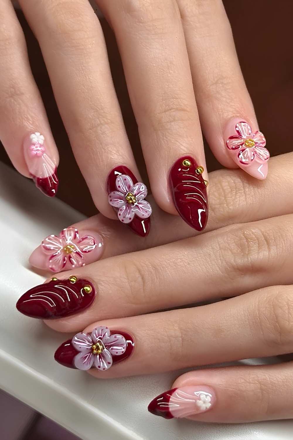 Deep red nails with textured floral art
