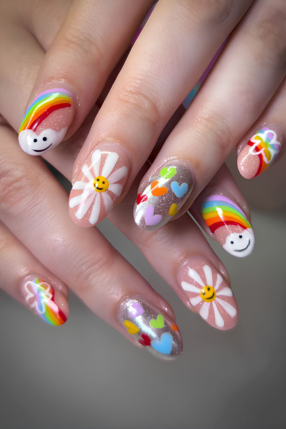 Glittery base nails with rainbows, hearts and smily daisy accent