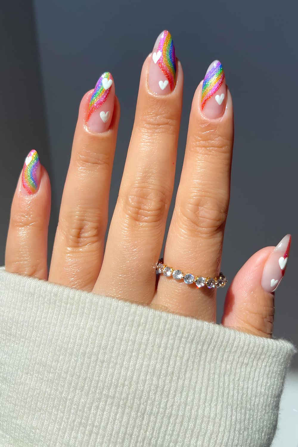Glittery rainbow swirl nails with tiny white heart designs