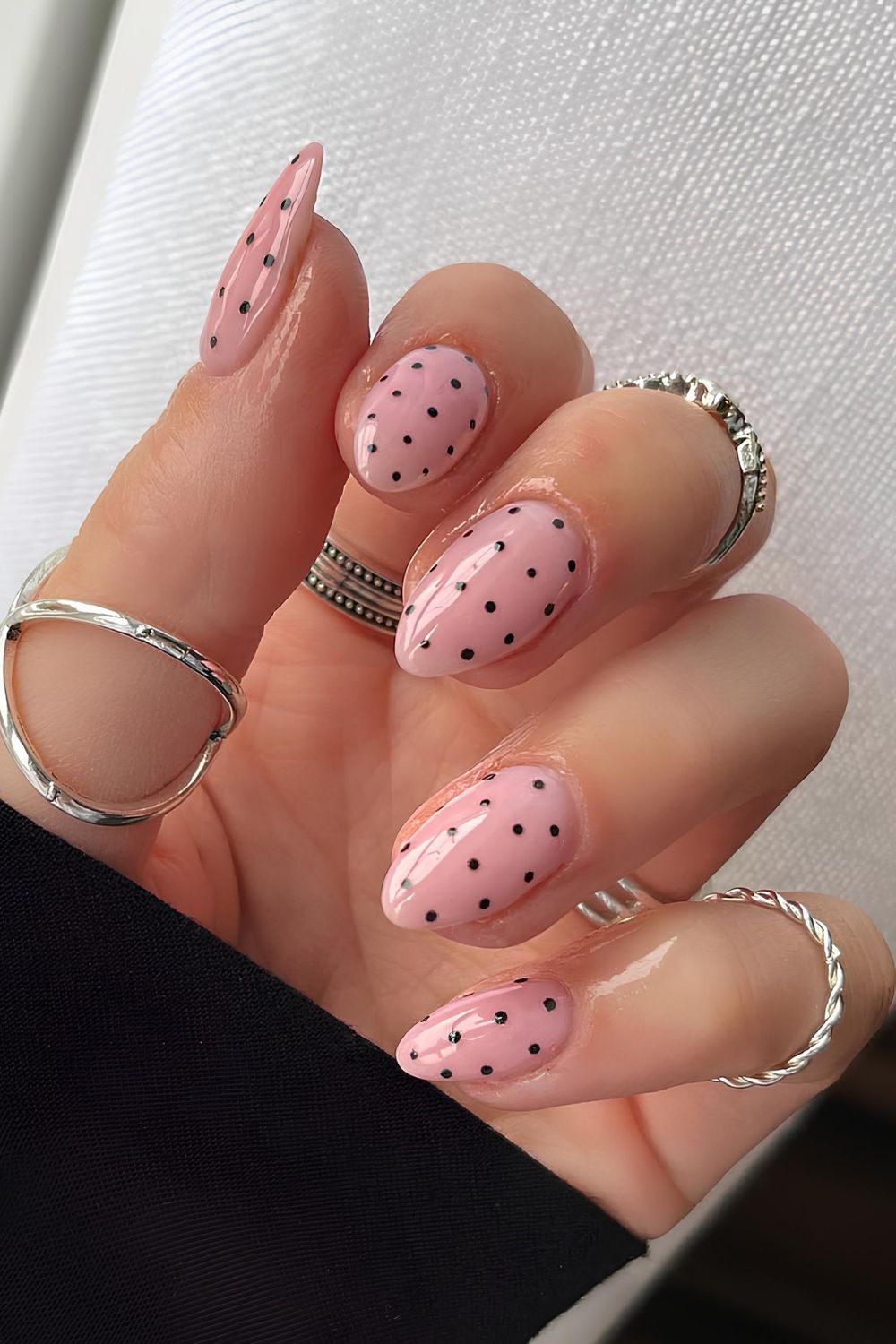 Glossy pink nails with black polka dots