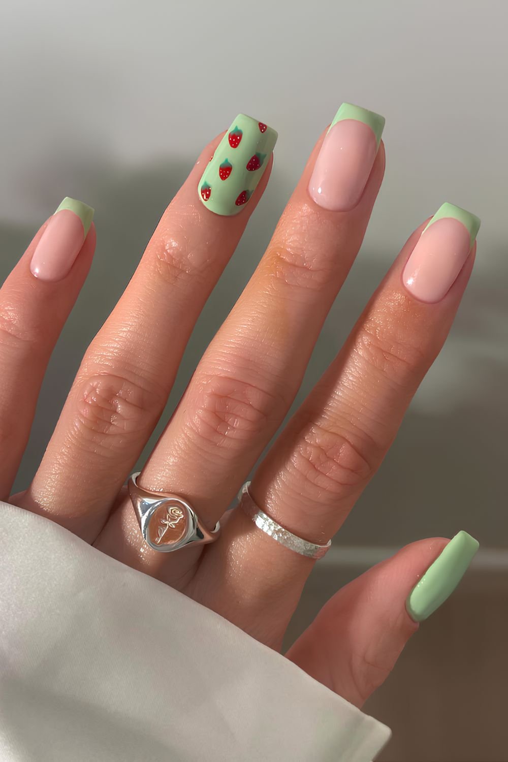 Green manicure with strawberry art