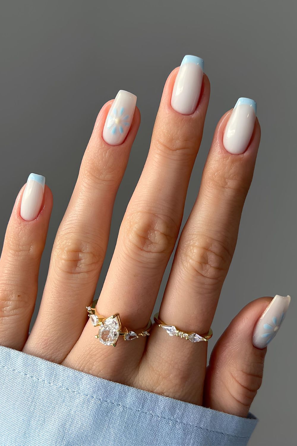 Light blue French tip nails with white base and flower accent
