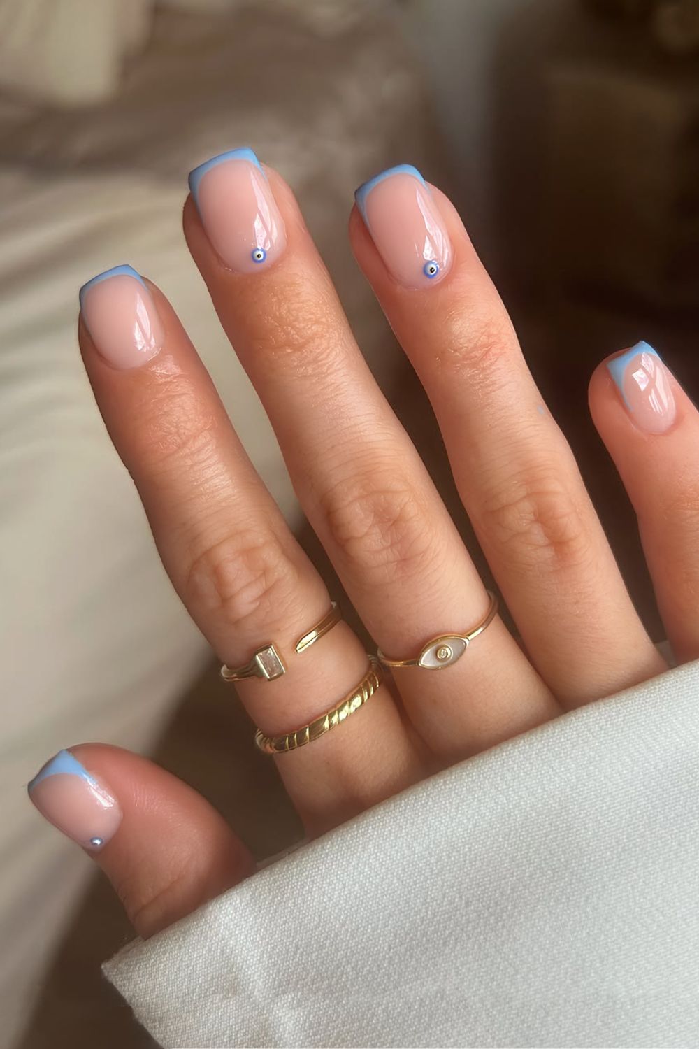 Light blue micro french tips with evil eye accents