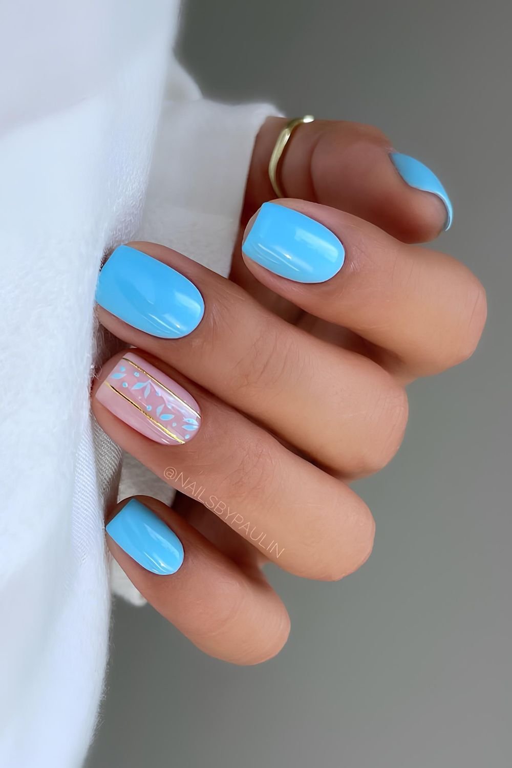 Light blue nails with gold lines and floral accent