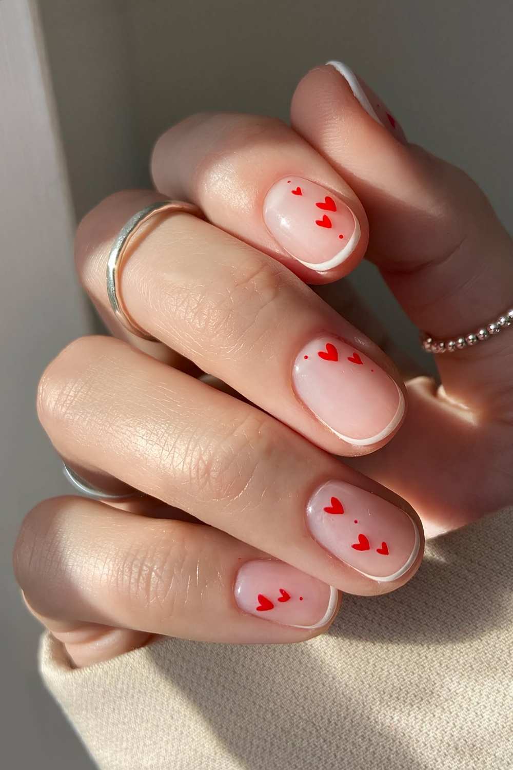 Micro white French nails with red hearts