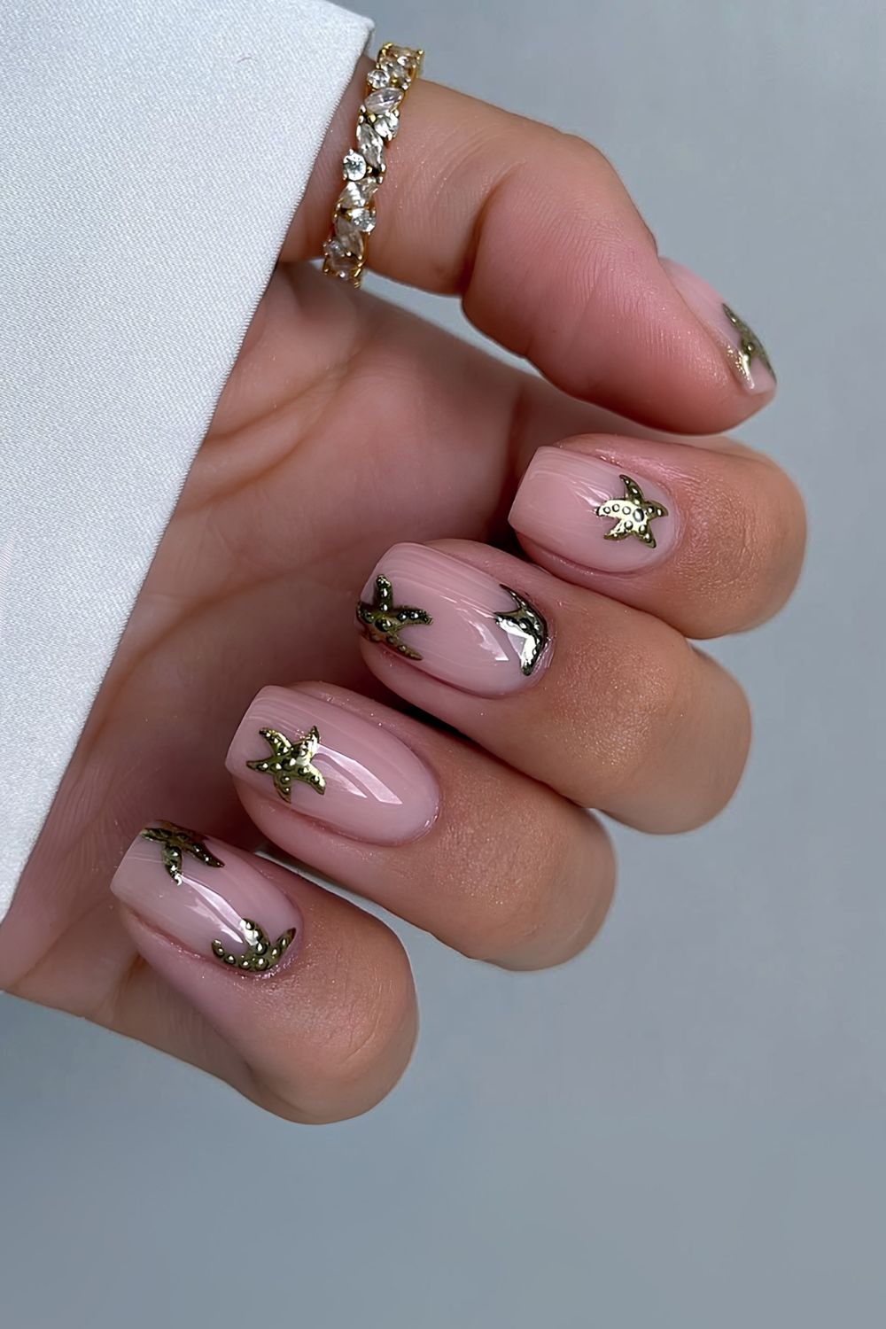 Milky pink nails and gold chrome starfish design