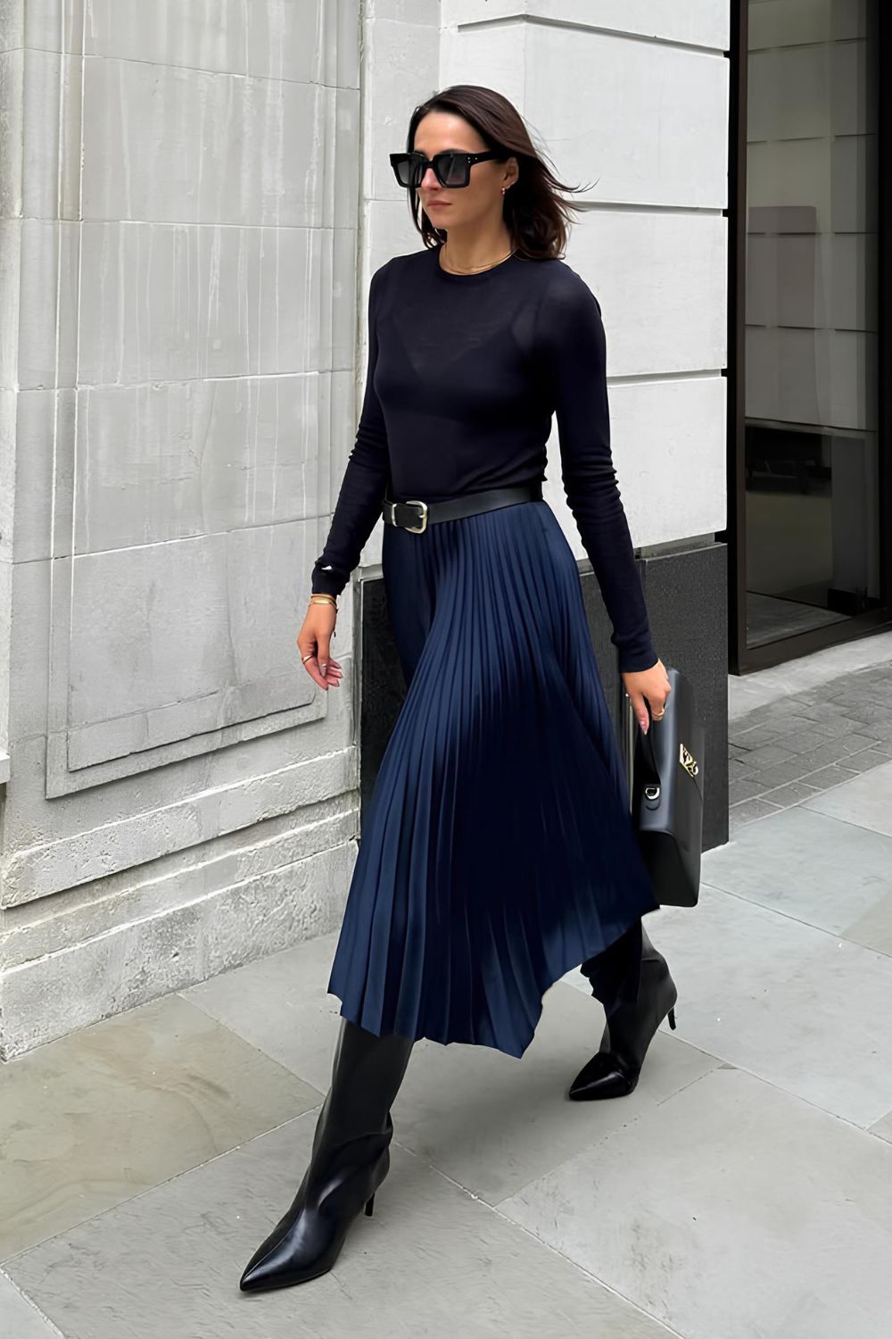 Navy blue pleated silk skirt paired with navy shirt and black boots