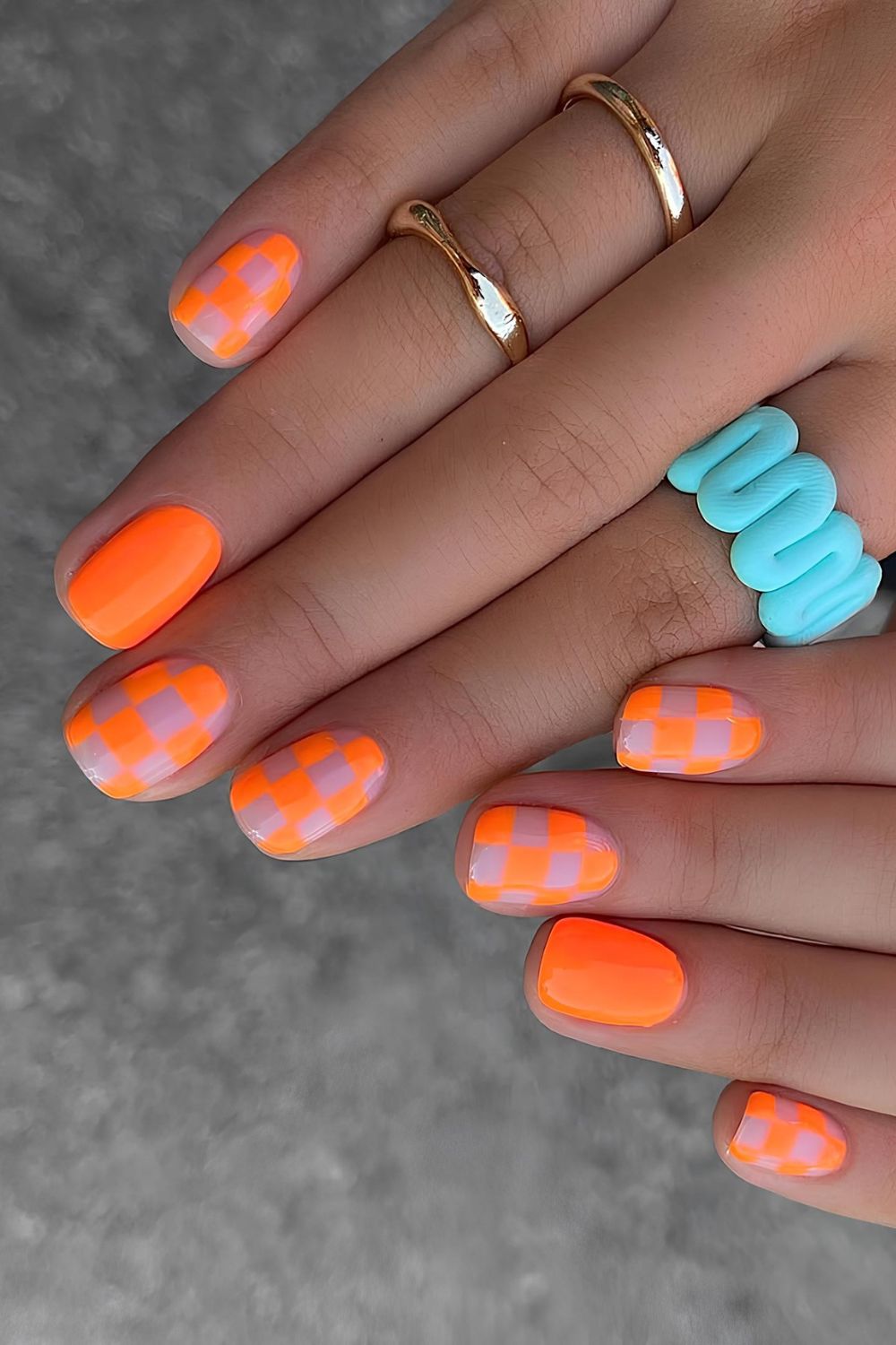 Neon orange nails with checkerboard design
