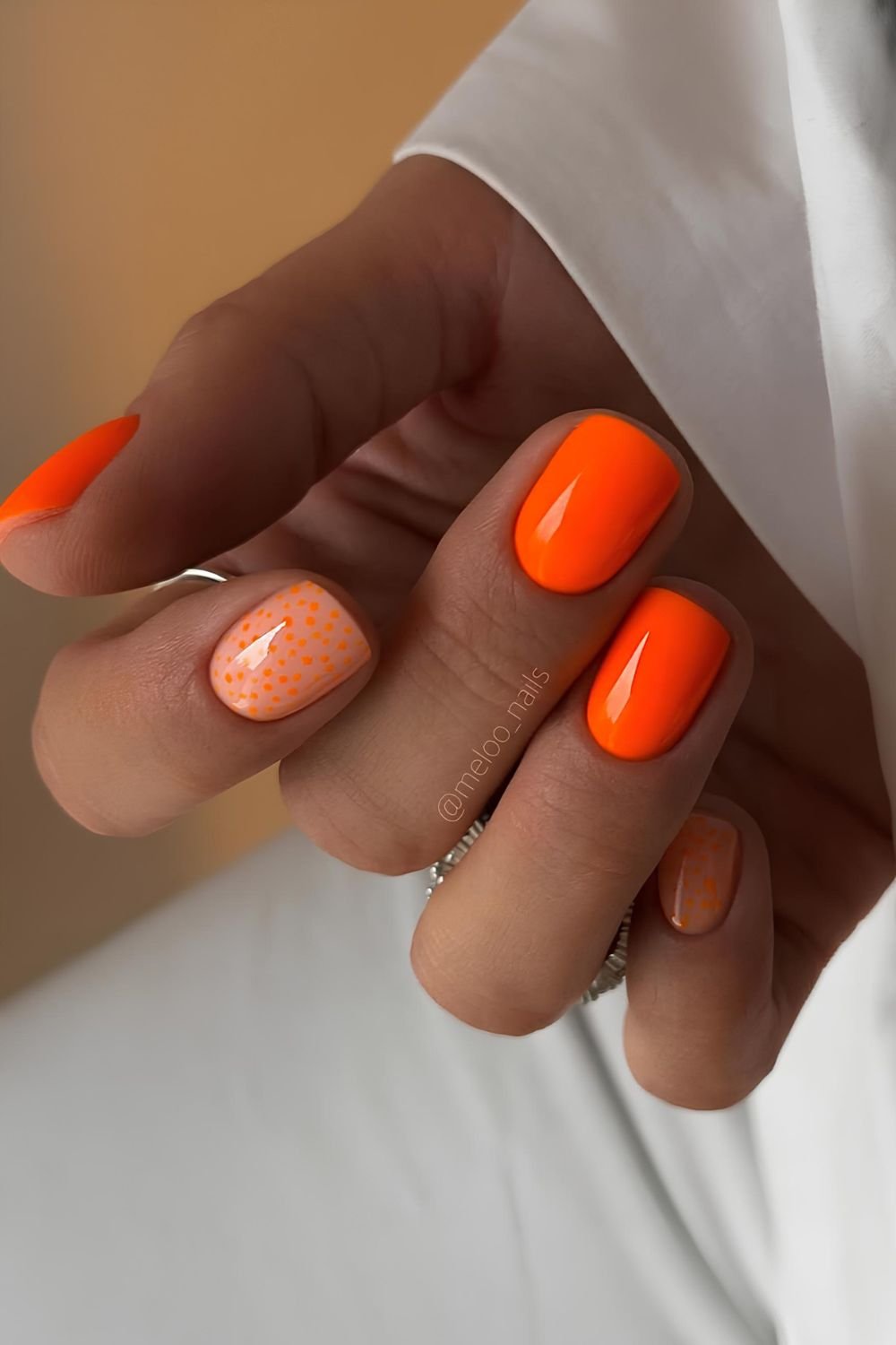 Neon orange nails with dot accents