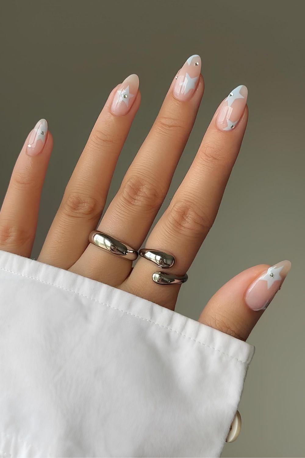 Neutral glowy nails with light blue stars and rhinestones