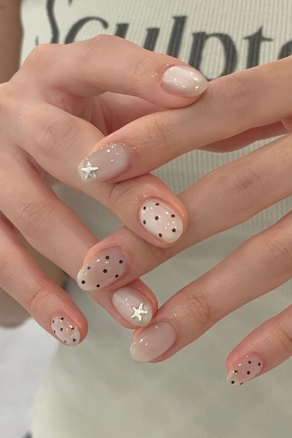 Neutral jelly nails with black polka dots and silver stars