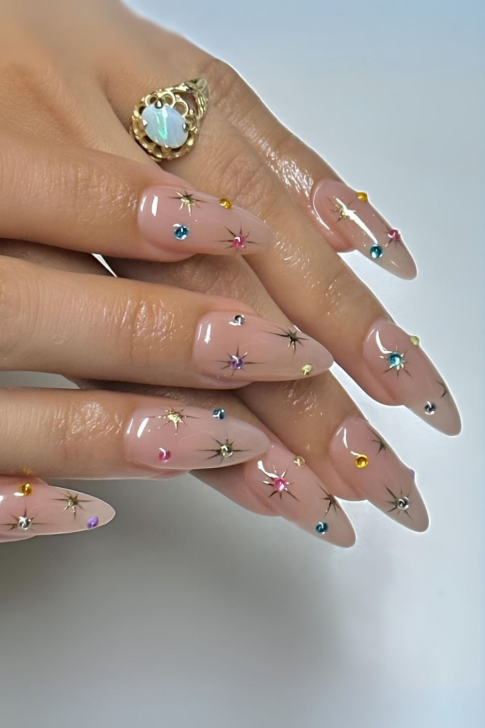 Neutral nails with colorful gems and golden chrome stars
