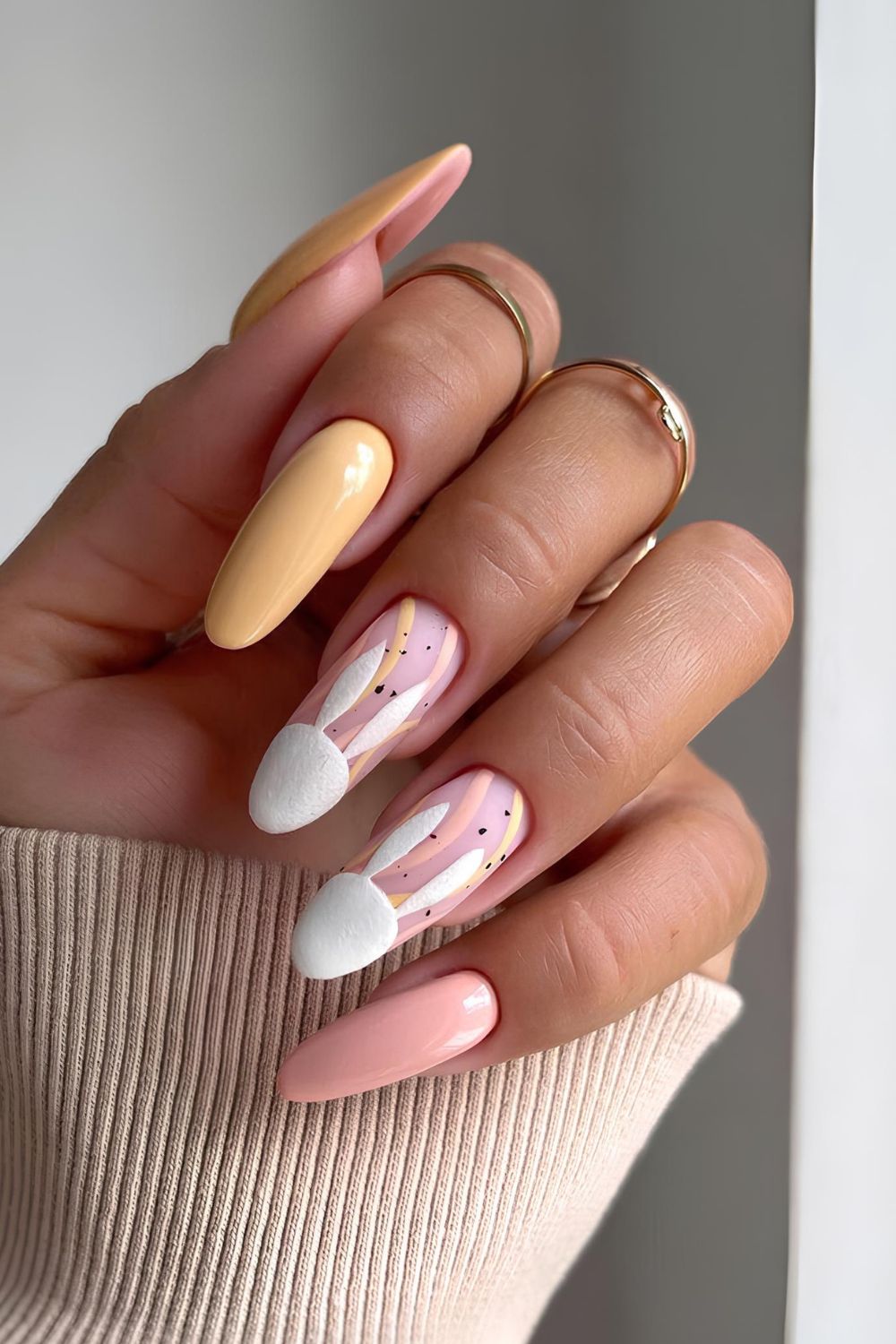 Pink and orange nails with bunny accents and swirls and dots