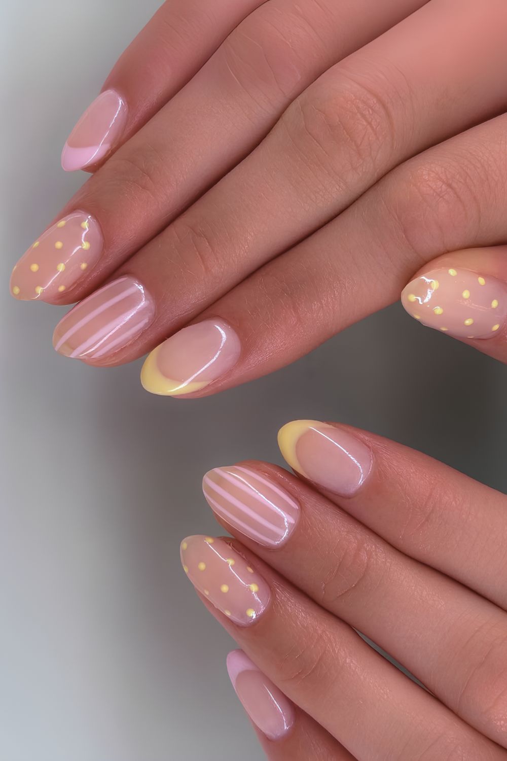 Pink and yellow nails with stripes and polka dots