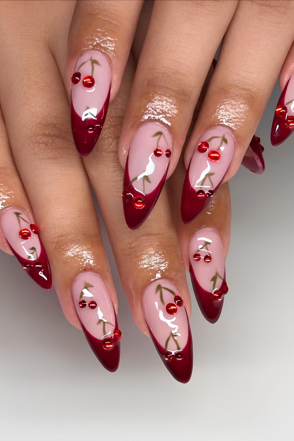 Red French tip nails with cherry rhinestone accents