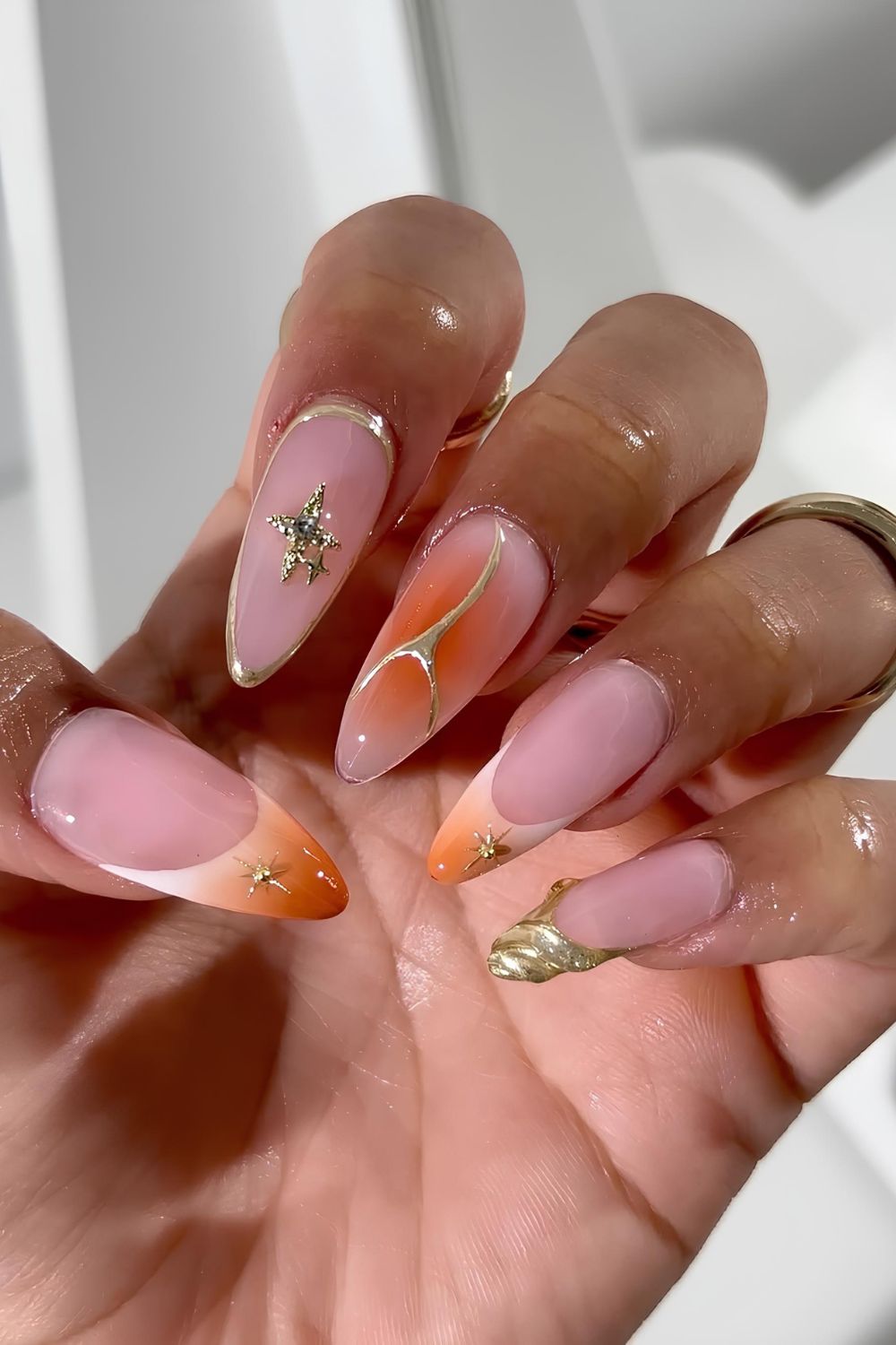 Sheer mani with orange aura effect and gold chrome accents