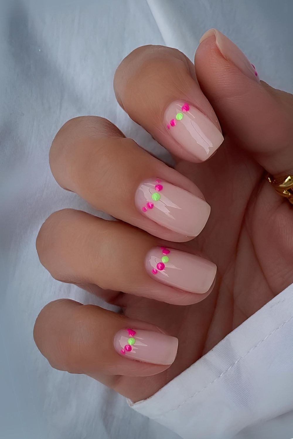 Short milky pink nails with dotted half moon accents