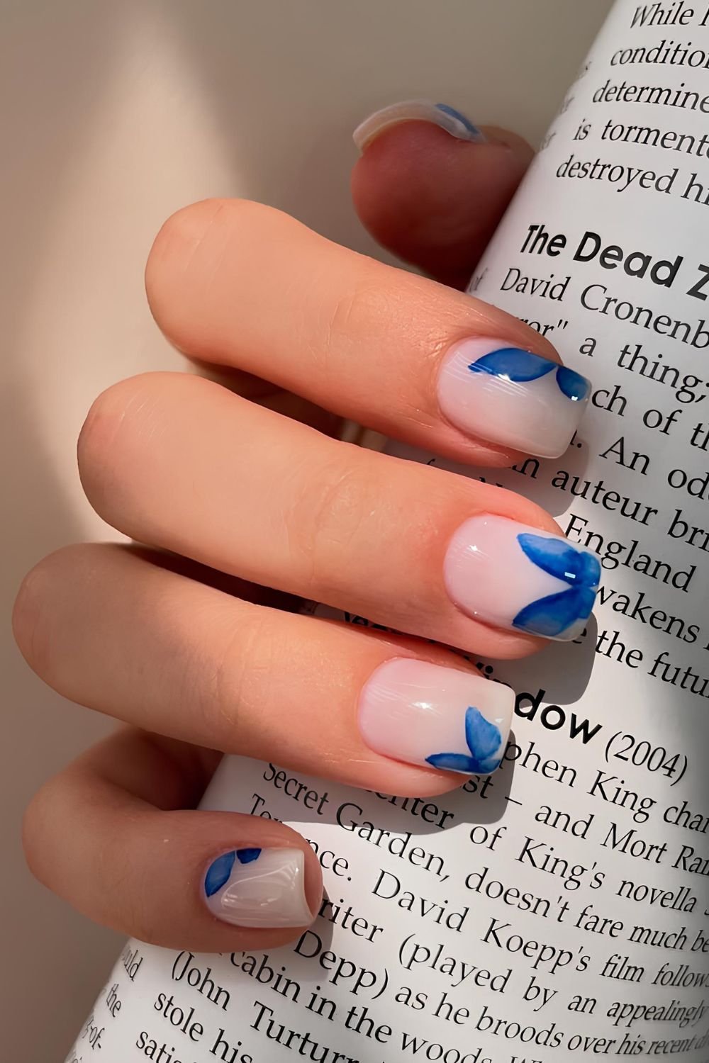 Short milky white nails with blue butterfly design