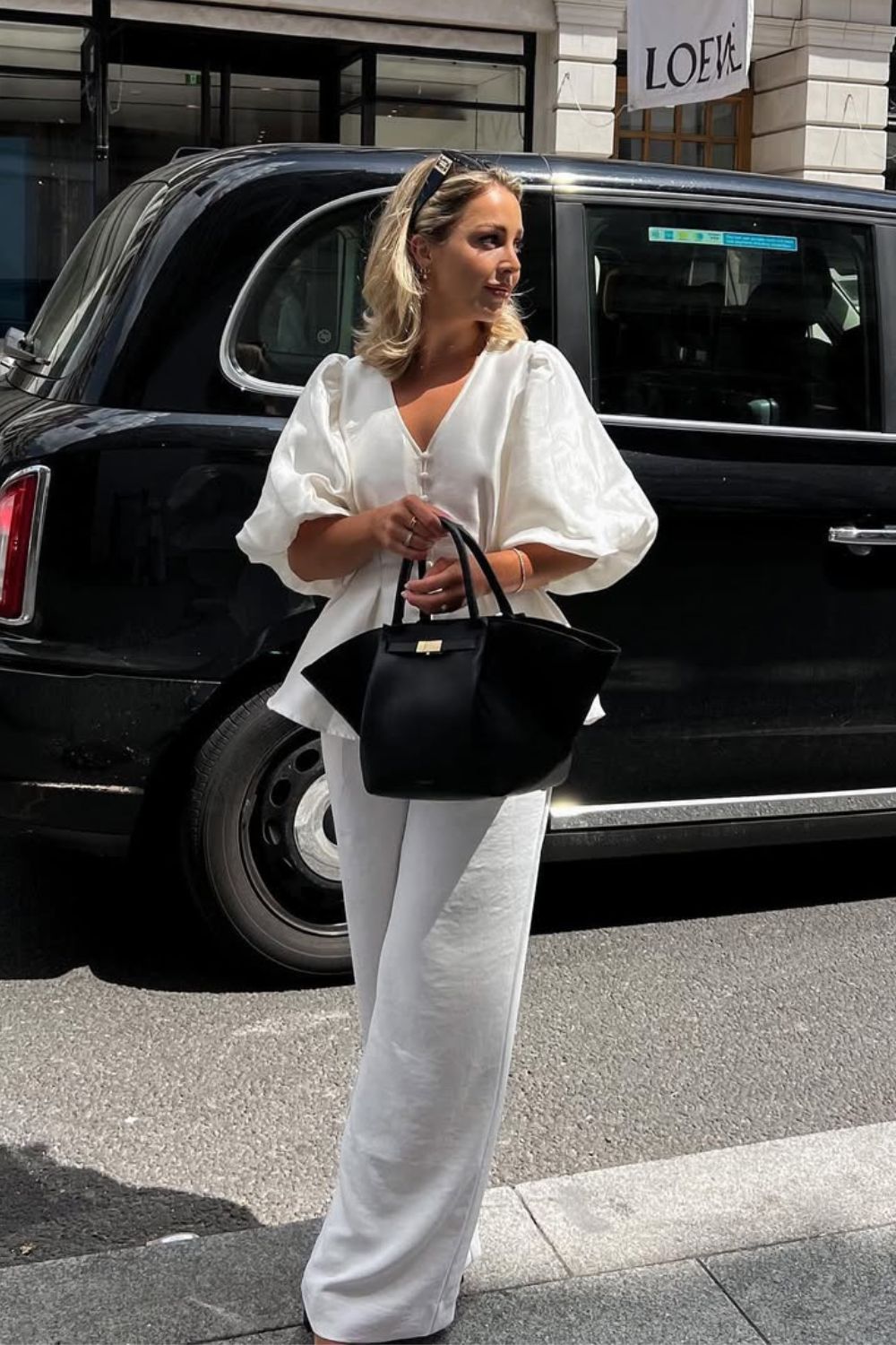 White wide leg pants paired with white matching shirt and black bag